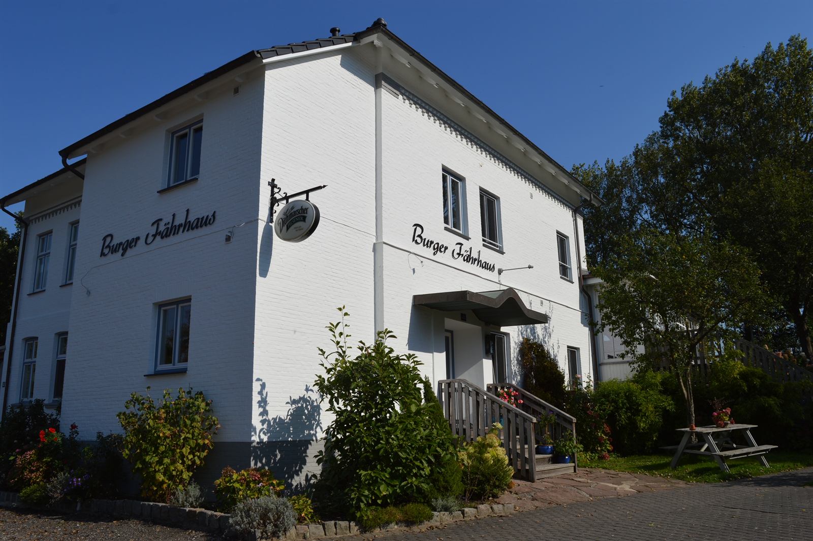 Gebäudeecke des Burger Fährhauses mit weißer Klinkerfassade und Schriftzug